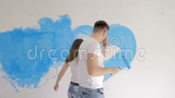 一家人用蓝色油漆把心画在墙上快乐日概念视频的预览图