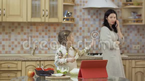 小女孩在厨房做新鲜沙拉的时候向妈妈挥手视频的预览图