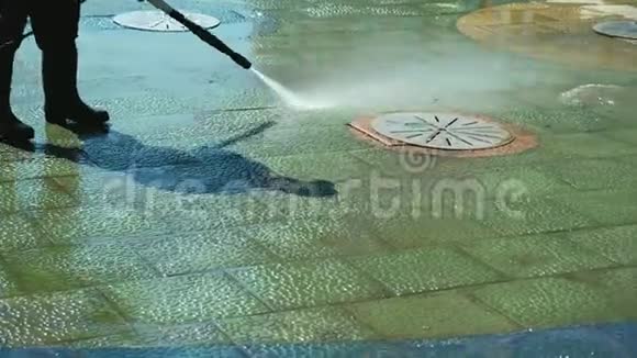 在市中心人行道附近的工人电力清洗路边用水管清洗城市街道清扫街道视频的预览图