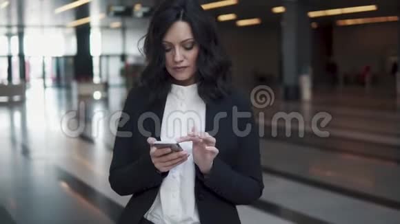 一位身着商务套装的妇女走过一座现代化办公楼的大厅女商人用手机视频的预览图