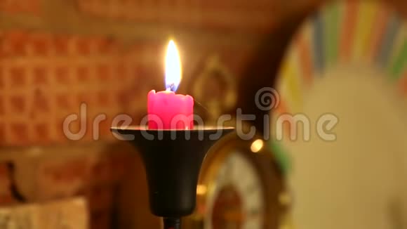 在黑色烛台上燃烧的红蜡烛站在砖砌的壁炉上后台时钟视频的预览图