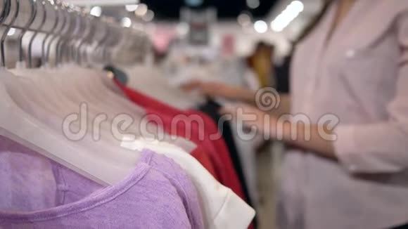 顾客女性在打折时在时装店的衣架上挑选新的时尚服装手拿不着重点视频的预览图