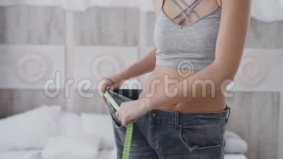 紧身衣一个身材运动的女人在减肥后测量她裤子的大小美丽的身体和平坦的胃视频的预览图
