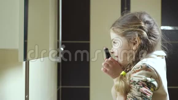 可爱的小女孩微笑着对着镜子握着手中的口红视频的预览图