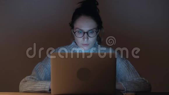 戴眼镜的可爱女人在黑暗的房间里上网视频的预览图