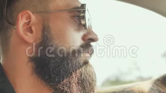 一个戴墨镜的长胡子的人开着一辆车视频的预览图