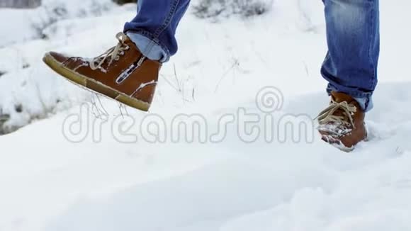 在深雪中行走的脚以慢动作射击徒步旅行者的脚步在美丽的风景中展现年轻人视频的预览图