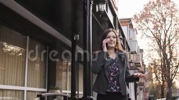 漂亮的白种人女商人在办公楼的背景下走在街上在电话里交谈视频的预览图