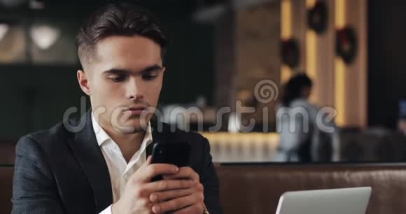 帅哥使用智能手机坐在咖啡馆或同事办公室企业家成功的肖像视频的预览图