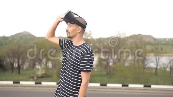 一个年轻人戴着虚拟现实头盔站在大自然面前潜水游戏或全景视频去的电影视频的预览图