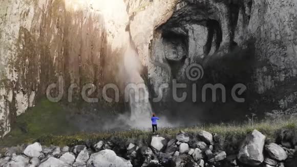 一个女孩是一个专业的风景摄影师站在河边的石头上拍摄一部大型史诗视频的预览图