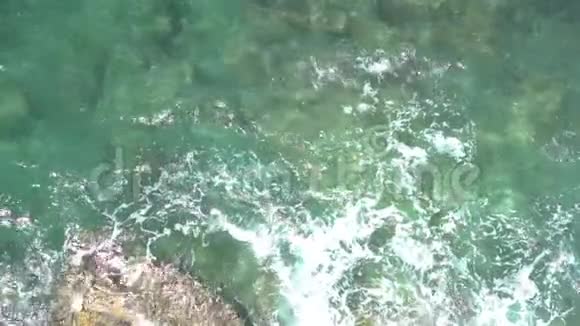 在阳光明媚的夏日海洋绿松石浪撞击在石滩上视频的预览图