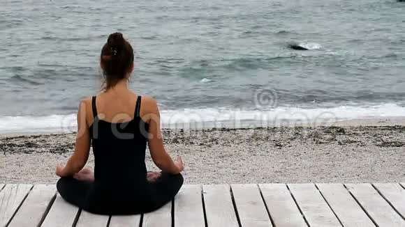 吉尔尔静静地坐在莲花的姿势中在海边沉思视频的预览图