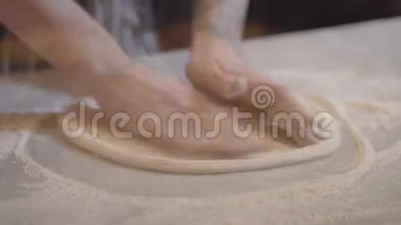 用围裙准备面团的年轻比萨饼制造商的手厨师做披萨视频的预览图