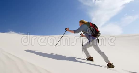 带着登山杆在沙丘上行走的人视频的预览图