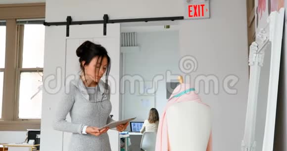 服装设计师使用平板电脑在4k型服装上检查面料视频的预览图