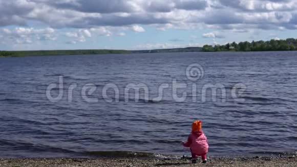 小可爱的女孩在池塘边玩石头慢动作视频的预览图