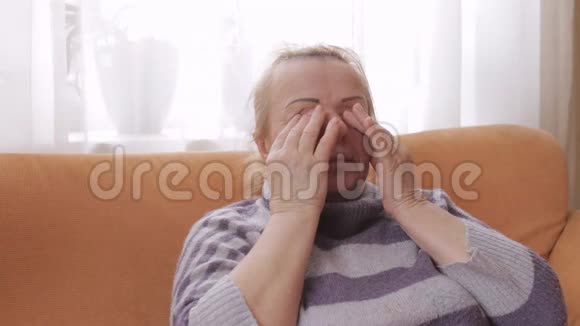 坐在沙发上的老年妇女揉揉眼睛视频的预览图