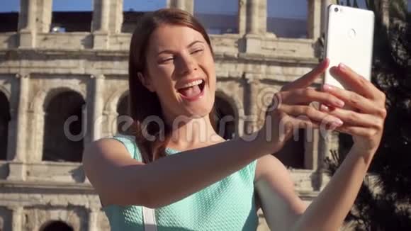 女人在意大利罗马竞技场附近的手机上自拍少女在慢动作中微笑视频的预览图