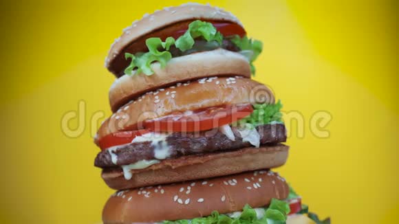 巨大美味的新鲜汉堡作为蛋糕旋转的黄色背景芝士汉堡配肉切块蔬菜奶酪视频的预览图
