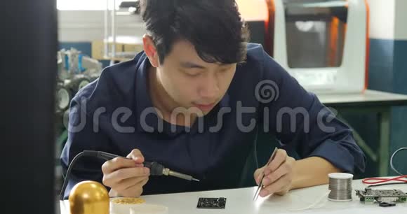 亚洲电子工程师正在他的车间焊接一块电电板视频的预览图