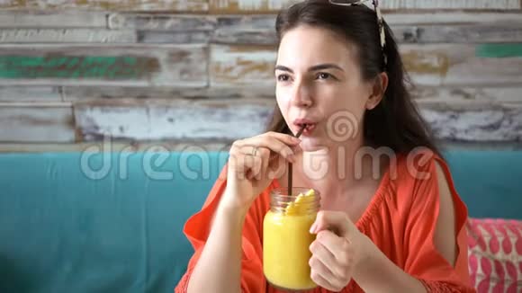 小姑娘喝着新鲜的热带芒果奶昔视频的预览图