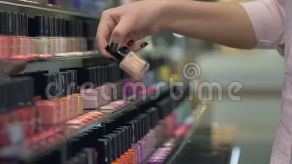 采购女孩选择指甲油美甲和修脚从大量瓶指甲油在商店橱窗视频的预览图