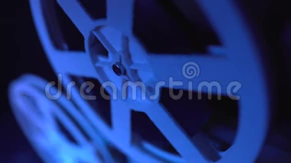 旧的8mm电影放映机晚上在带蓝光的暗室放映电影卷轴的特写慢动作老式视频的预览图
