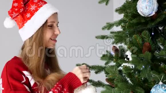 圣诞老人帽子上装饰圣诞树的快乐年轻女子视频的预览图