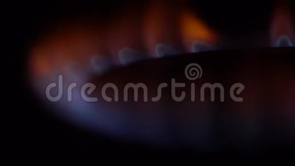 黑暗中燃烧的炉子火的特写在黑暗中厨房用弱火关闭工作燃气燃烧器视频的预览图