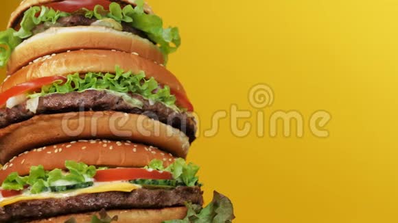 巨大的新鲜汉堡作为蛋糕旋转和从顶部倒入蛋黄酱脂肪酱黄色背景快餐不健康视频的预览图