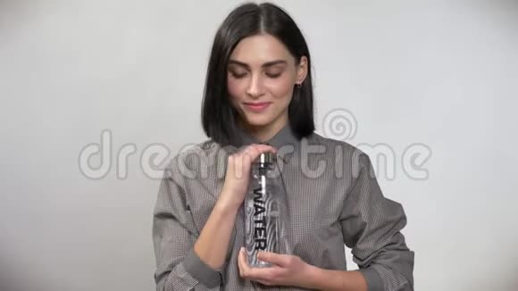 年轻的美女棕色短发拿着瓶子拿着水相机指着瓶子微笑着快乐着视频的预览图