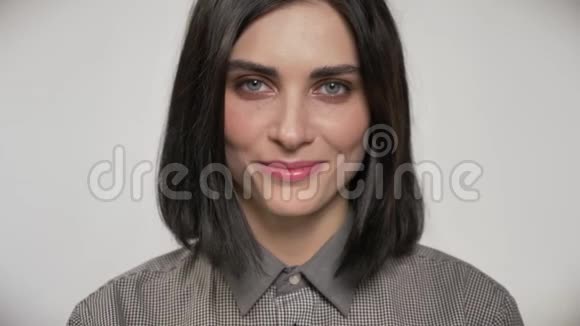 年轻美丽的女人的肖像棕色短发直视镜头笑白色背景视频的预览图