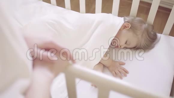 一个穿着白色衣服的女人站在婴儿床旁边婴儿床上睡着一个小孩视频的预览图