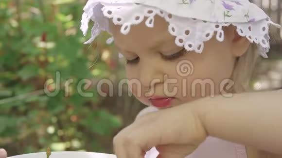 一个小女孩在花园里吃新鲜的红樱桃视频的预览图