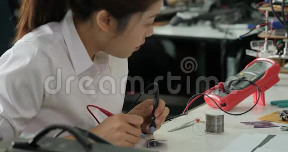 女电子工程师正在她的车间测量电路中的信号视频的预览图