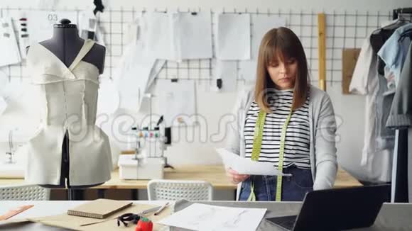 专业的服装设计师通过素描添加一些细节并在她的灯光下检查笔记本电脑视频的预览图