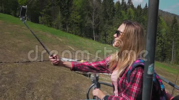 年轻女子乘坐山上电梯使用智能手机和自拍森林背景视频的预览图