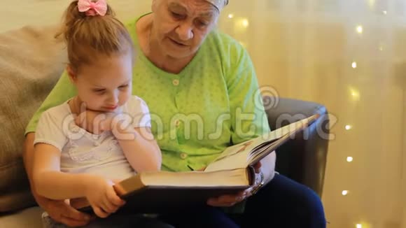 外婆和孙女一起读童话书祖母拥抱她的孙女视频的预览图
