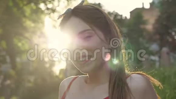 年轻漂亮的女人的肖像姜发对着镜头微笑坐在草地上阳光灿烂视频的预览图