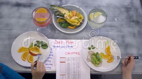 健身饮食女孩吃蔬菜和水果的盘子坐在桌子上有卡路里和饮食计划视频的预览图