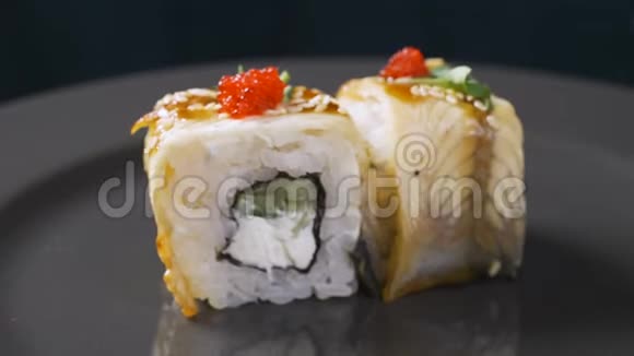 寿司卷日本食品旋转在黑色背景寿司卷配鳗鱼鱼子酱和鳄梨特写旋转视频的预览图