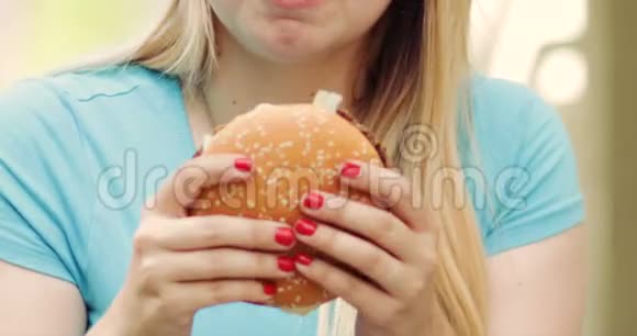 女人吃汉堡用两只手握着视频的预览图