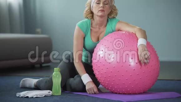 精疲力竭的成熟女性躺在健身球上积极锻炼后放松视频的预览图
