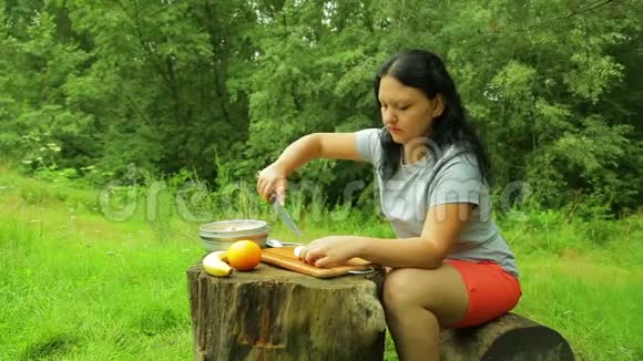 一个年轻的女人正在把一个苹果切成薄片作为早餐的水果沙拉视频的预览图