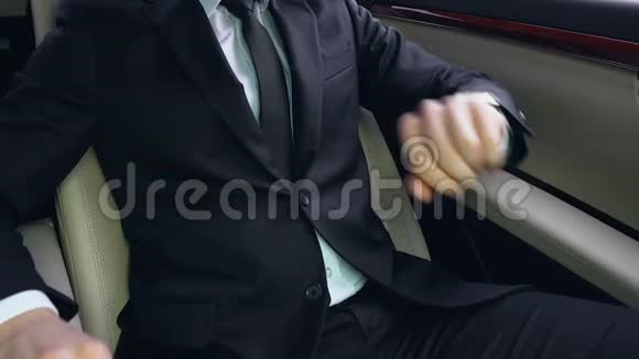 商人坐在汽车后座上看着手表卡在交通中视频的预览图