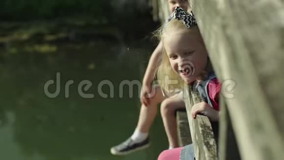 儿童坐在桥上的肖像在夏季公园观看河流慢动作全高清视频的预览图