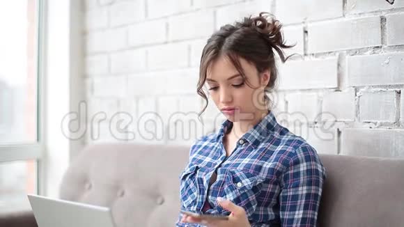 女自由职业者在家工作在手机上键入一条短信她穿着一件蓝色格子衬衫视频的预览图