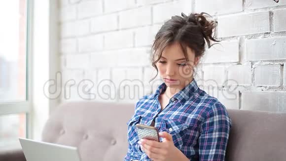 女自由职业者在家工作她打电话开始交谈她穿着一件蓝色格子衬衫视频的预览图