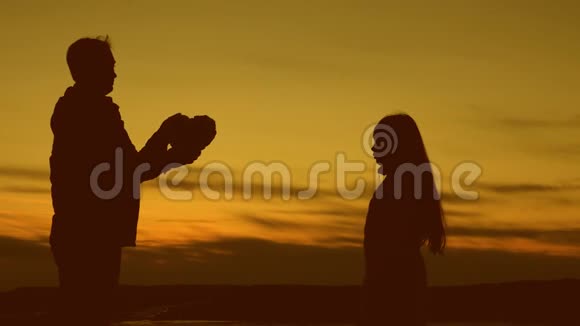 一个十几岁的女孩和她父亲在日落时抱着一颗温暖的心视频的预览图